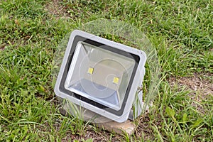 Led waterproof lamp, spotlight installed on a grass of a lawn in the garden in city park for illumination of paths