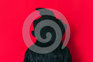 Ledy in a witch costume facing a red background