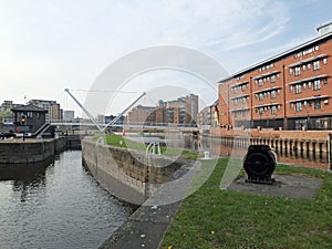 the leeds lock entrance to clarence dock with footbridge over the river aire and historic gates and mooring area surrounded by