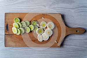 leek slices on a wooden board, ready to prepare delicious soup