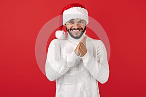 Leery hipster man wears santa claus hat over red background. Christmas and New Year concept.