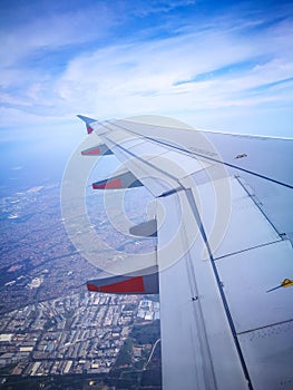 A Left Aircraft wing flying on the sky above the city.