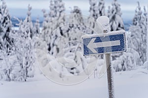 Left arrow traffic sign covered with frost on a cold winter day