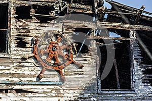 The left deck of an old wooden ship that has undergone a fire against a ship`s rudder.