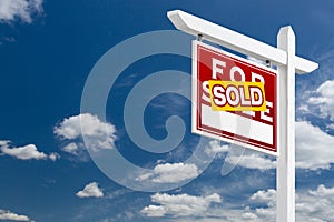 Left Facing Sold For Sale Real Estate Sign Over Blue Sky and Clouds With Room For Your Text.