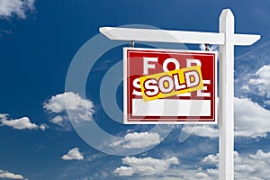 Left Facing Sold For Sale Real Estate Sign Over Blue Sky and Clouds With Room For Your Text.