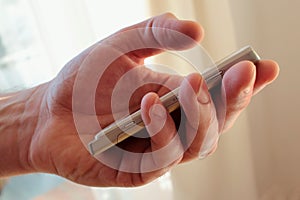 Left hand of man holding white silver cell mobile phone