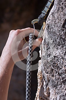 Left hand passing climbing black and white rope though the carabiner.