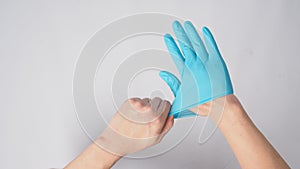 Left hand is pulling right hand with blue latex gloves on white background