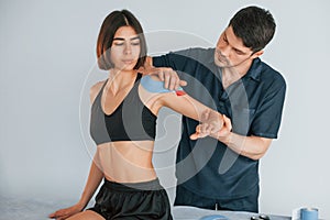 On the left hand. Woman visiting physiologist that putting kinesio tape on the skin photo
