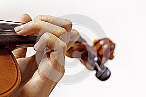 left hand of a young violinist on the strings on a student's violin on a light background.