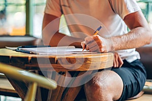 Left handed man hand with pen writing on notebook