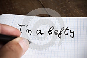 Left-handed man handwriting the text I am a lefty photo