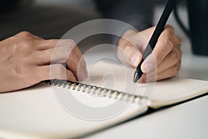 Left handed man writes in a notebook on the table