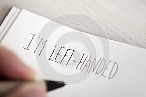 Left-handed man writing the text I am left-handed