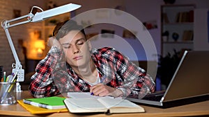 Left-handed overloaded teenage student preparing for examination, feeling sleepy