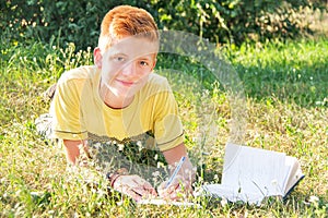 Left-handed teen lying and reading on the grass.