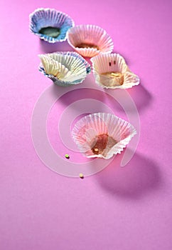 Leftover muffin papers on pink background