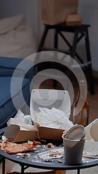 Leftover of pizza, empty beer bottles and napkins on misery table and floor