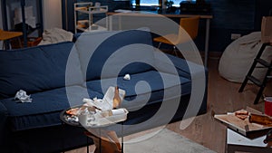 Leftover of pizza empty beer bottles and napkins on table in messy living room