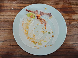 leftovers on a white plate on wooden texture background.