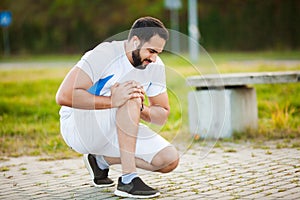 Leg Injury. Male athlete suffering from pain in leg while exercising outdoors