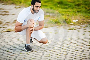 Leg Injury. Male athlete suffering from pain in leg while exercising outdoors