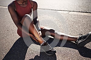 Leg, injury and pain with a sports black woman holding her ankle outdoor during a fitness workout from above. Ankle