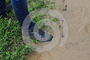 A leg in jeans and sneakers is buried in the water after rain outside the city