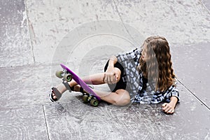 Leg and knee injury on penny board. Child traumatology. Child girl falling from skate board and get injured and feeling