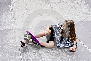 Leg and knee injury on penny board. Child traumatology. Child girl falling from skate board and get injured and feeling