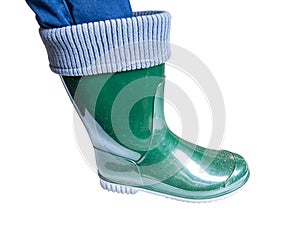 The leg of a man in a green rubber boot on a white background