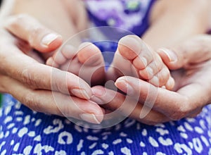 Leg of a newborn baby in the hands of parents. Mom and dad show care for their child. The concept of protecting a defenseless baby