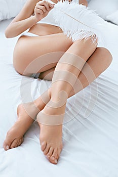 Leg Skin. Woman Touching Long Legs With Smooth Skin With Feather