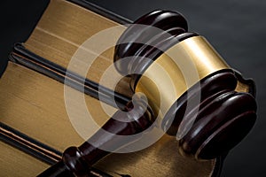 Legal code enforcement and courtroom proceedings concept with a gavel on a stack of law books with gold rim with dramatic lighting photo