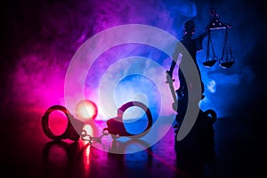 Legal law concept. Silhouette of handcuffs with The Statue of Justice on backside with the flashing red and blue police lights at