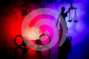 Legal law concept. Silhouette of handcuffs with The Statue of Justice on backside with the flashing red and blue police lights at