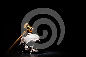 Legal law, justice and murderment concept. Wooden judge gavel hammer on human skull with handcuffs against black background. Free