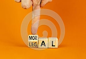 Legal or moral symbol. Businessman turns wooden cubes and changes the word Legal to Moral on a beautiful orange table orange