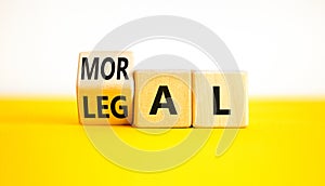Legal or moral symbol. Businessman turns wooden cubes and changes the word Legal to Moral on a Beautiful yellow table white