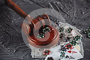 Legal rules for online gambling concept. Wooden gavel, money banknotes and playing cards on grey background