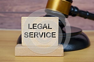 Legal service text engraved on wooden block with gavel background. Legal and law concept.