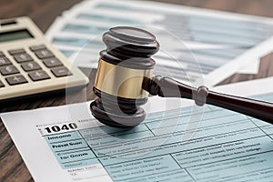 Legal symbol gavel on tax form with calculator signifies financial implication and obligations.