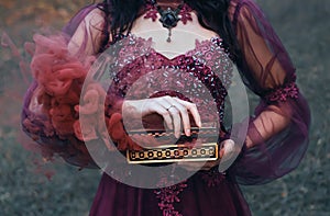 Legend of Pandora`s box, girl with black hair, dressed in a purple luxurious gorgeous dress, an antique casket opened