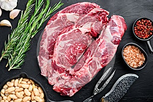 Legendary Ribeye fresh raw beef steak with spices and white beans, on black stone background, top view flat lay