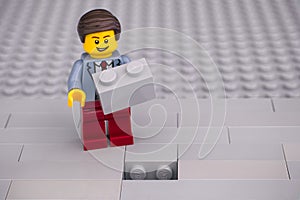 Lego businessman with brick ready to fill a hole