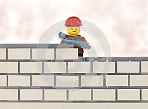 Lego minifigure worker by brick wall building