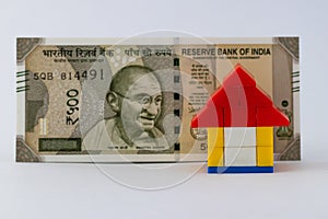 A lego house put in front of one five hundred rupee note representing house loan concept