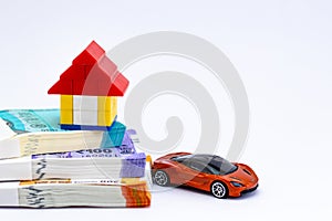 A lego house, sports car, and money notes shot against white background showing loan concept