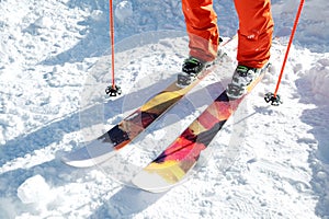 Legs athlete skier in an orange overall on a sport skiing on snow on a sunny day. The concept of winter sports